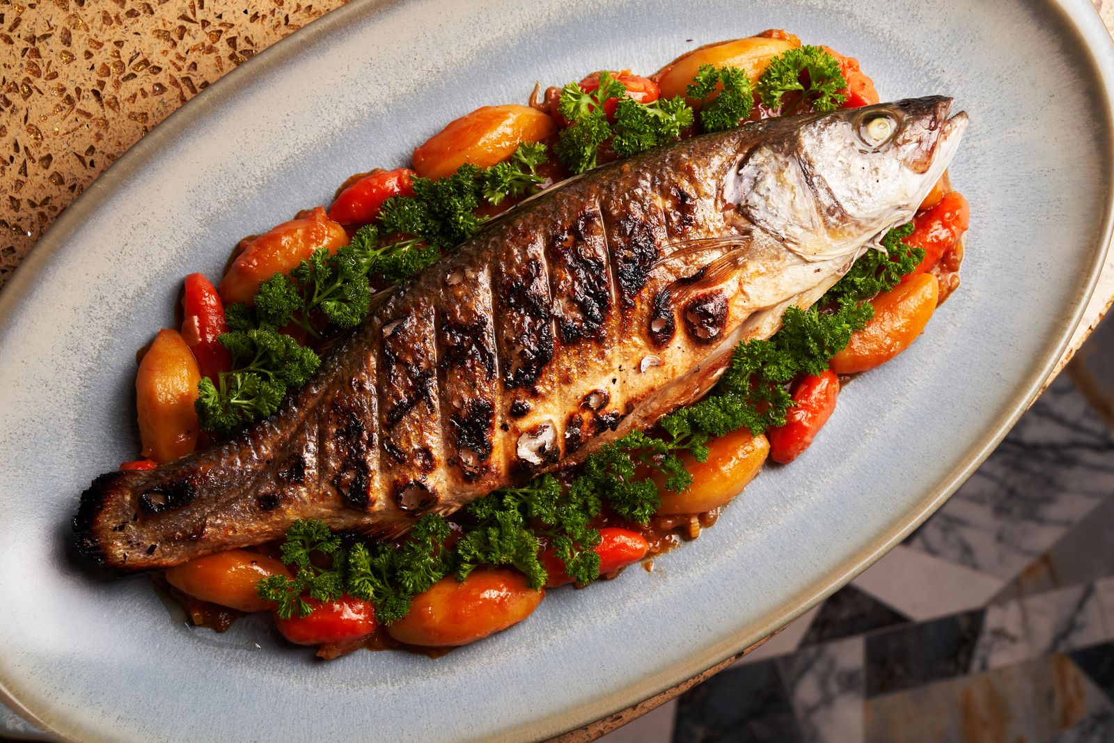 Poisson entier grillé présenté avec des légumes